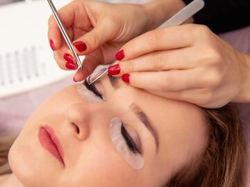 Eine Frau bekommt eine dauerhafte Wimpernverlängerung | © GettyImages/CasarsaGuru