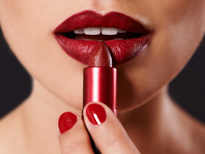 Frau schminkt dunkelrote Lippen | © Getty Images/PeopleImages