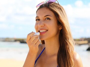 Frau trägt am Strand Labello auf ihre Lippen | © Getty Images/sergio_pulp
