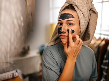 Eine Frau hat eine Maske auf dem Gesicht, um ihre Poren zu verkleinern | © GettyImages/mixetto