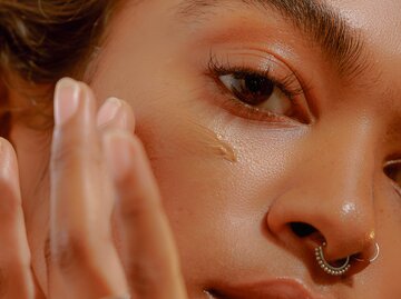 Eine junge Frau cremt sich ihre schöne Haut ein | © GettyImages/Caroline Tompkins /Refinery29