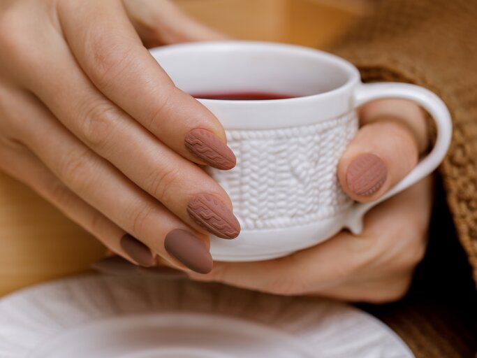 Winterliches Bild mit braunen Nagellack-Farben und Kaffee in der Hand | © Getty Images/Olesya Eroshenko