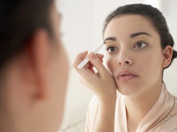 Frau zupft sich vor dem Spiegel die Augenbrauen | © Getty Images/Christopher Robbins