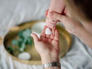 Frau cremt Hände mit Handcreme ein | © Getty Images/Emilija Manevska