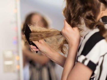 Frau kämmt splissige Haare | © Getty Images/Elva Etienne