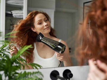 Frau mit roten Haaren föhnt sich | © Getty Images/Anna Bizon/EyeEm