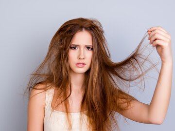 Frau packt sich an ihre verknoteten Haare | © Getty Images/Deagreez