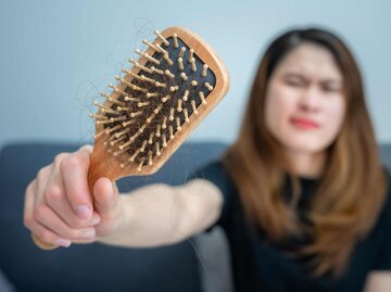 Frau hält verschmutzte Haarbürste in die Kamera | © Getty Images/Boy_Anupong