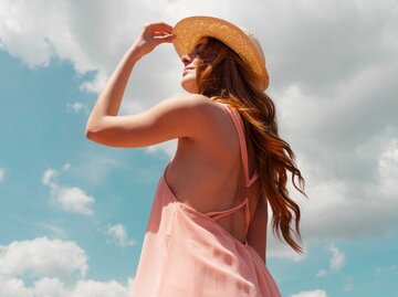 Portrait von schöner Frau mit gepflegten langen Haaren in der Sonne mit Sonnenhut | © Getty Images/Westend61