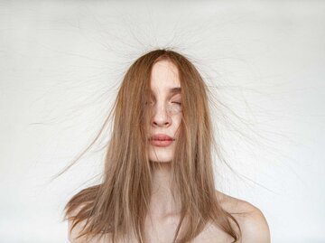 Junge Frau mit geschlossenen Augen und fliegenden, dünnen Haaren | © Getty Images/Iuliia Isaieva