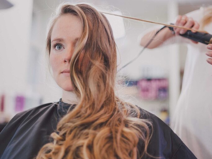 Blonde Frau sitzt beim Friseur und bekommt Locken  | © Getty Images/Guido Mieth