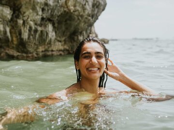 Eine Frau, die bis zu den Schultern im Meer steht | © Getty Images/Catherine Falls Commercial