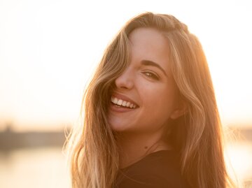 Lächelnde junge Frau mit glänzendem Haar, die in die Kamera blickt | © GettyImages/Martin Novak