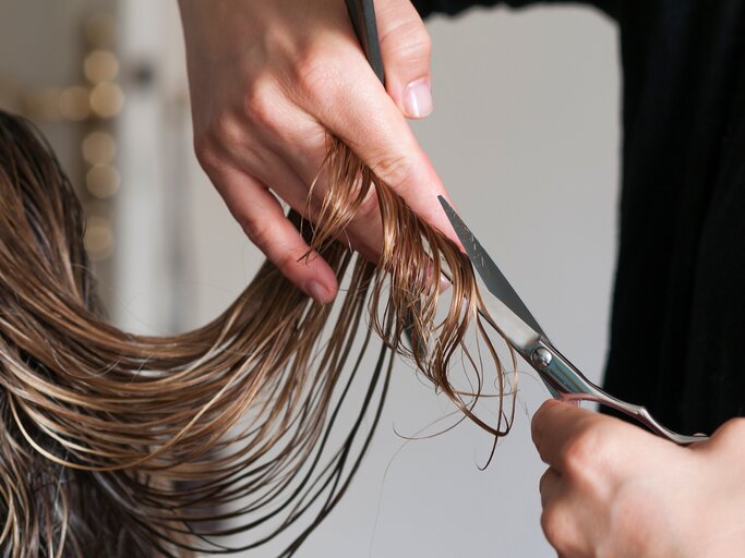 Hände schneiden mit einer Friseurschere lange Haare ab | © AdobeStock/up-foto