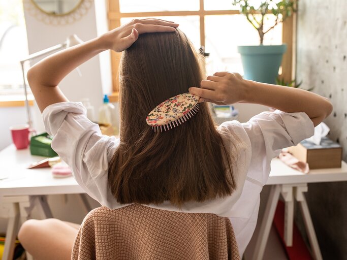 Junge Frau kämmt sich ihre Haare, von hinten | © GettyImages/Cicy