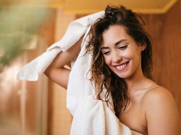 Junge Frau rubbelt sich mit einem Handtuch im Bad die Haare trocken | © Getty Images/Drazen Zigic