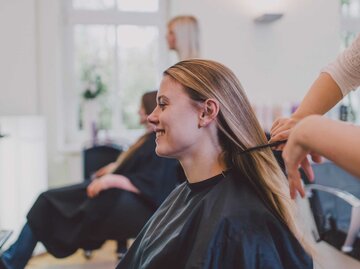 Frau sitzt beim Friseur und lässt sich die Haare schneiden | © Getty Images/Guido Mieth