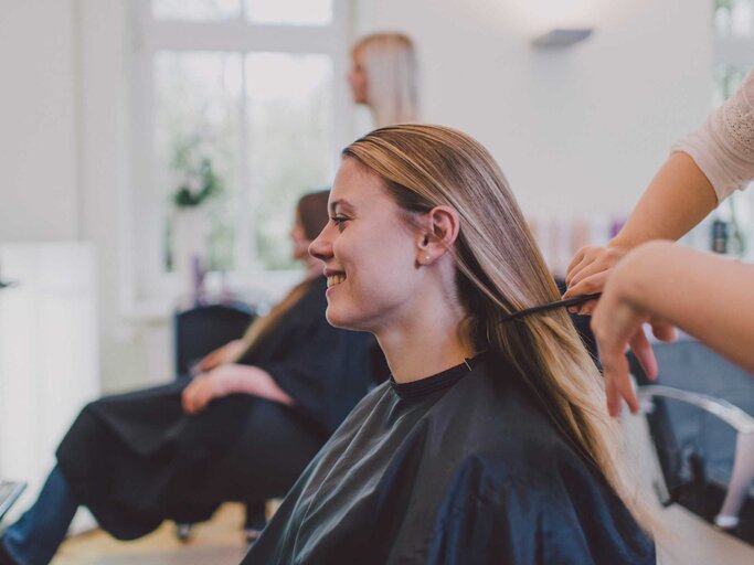 Frau sitzt beim Friseur und lässt sich die Haare schneiden | © Getty Images/Guido Mieth
