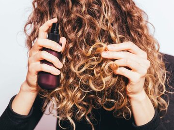 Person sprüht Haarspray in Haare | © Getty Images/iprogressman