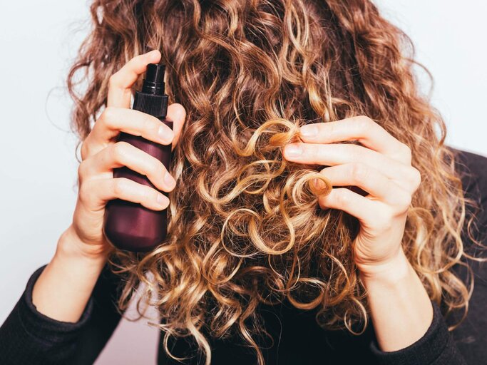 Person sprüht Haarspray in Haare | © Getty Images/iprogressman