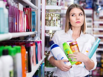 Frau mit Shampoo-Flaschen vor dem Regal | © Getty Images/JackF