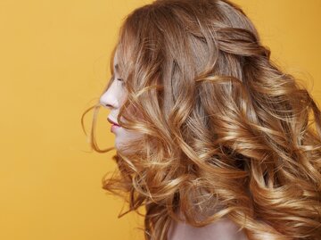 Frau mit glänzend lockigem Haar | © Getty Images/KrisCole
