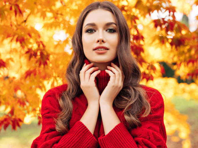 Frau in rotem Rollkragenpulli vor Herbstblättern | © Getty Images/CoffeeAndMilk