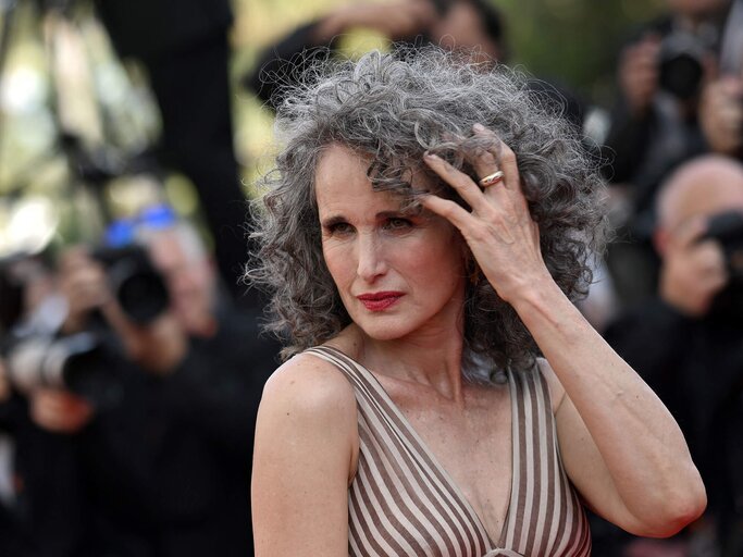 Andie MacDowell fasst sich in ihr graues Haar | © Getty Images/LOIC VENANCE