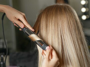 Haare werden mit dem Lockenstab gestylt | © Getty Images/pavlyukv