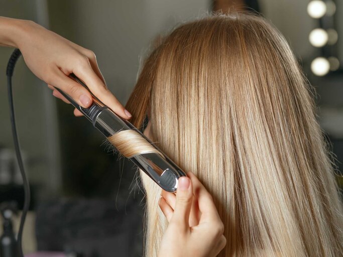 Haare werden mit dem Lockenstab gestylt | © Getty Images/pavlyukv