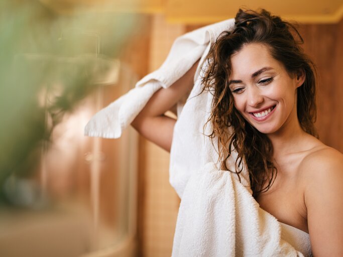 Frau trocknet sich nach dem Duschen die Haare mit Handtuch | © Getty Images/Drazen Zigic
