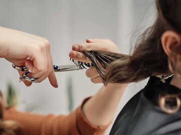 Frau schneidet beim Friseur ihre Haare. | © Getty Images / SBenitez