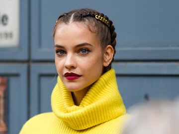 Junge Frau mit einem gelben Pullover trägt kirschrote Lippen. | © Getty Images / Edward Berthelot