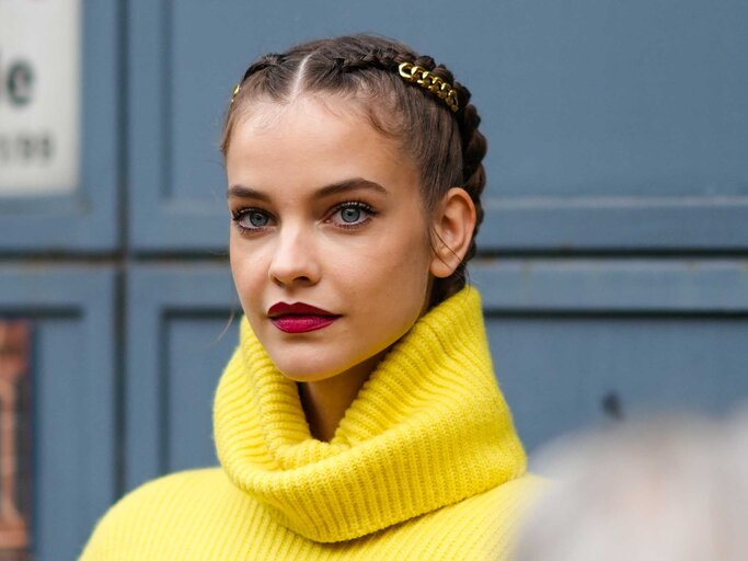 Junge Frau mit einem gelben Pullover trägt kirschrote Lippen. | © Getty Images / Edward Berthelot