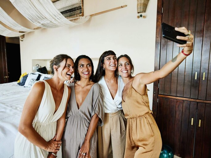 Gruppe auf Hochzeit macht Selfie | © Getty Images/Thomas Barwick
