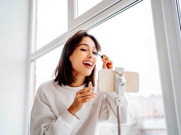 Frau trägt Mascara vor dem Spiegel auf | © Getty Images/Westend61