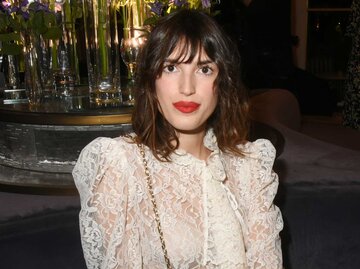 Jeanne Damas mit roten Lippen in weißer Spitzenbluse | © Getty Images/Foc Kan