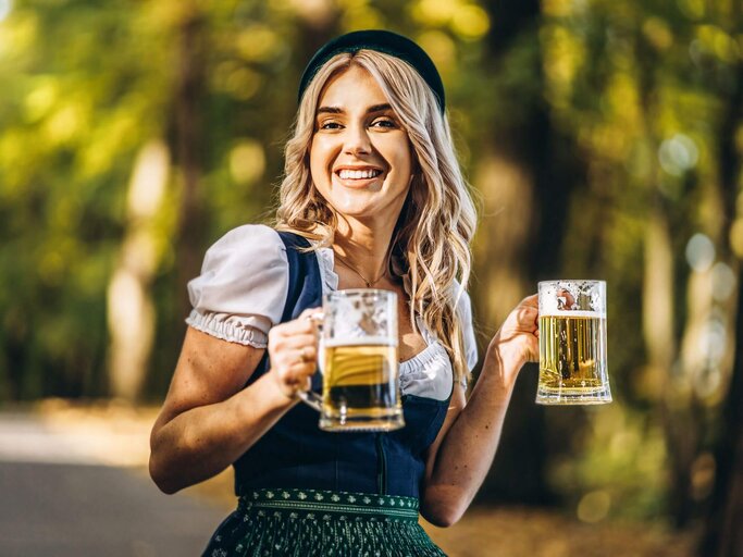 Person im Dirndl und mit Maßkrügen | © Getty Images/bedya