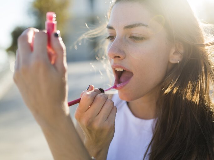 Frau trägt sich roten Lippenstift auf | © Getty Images/Westend61