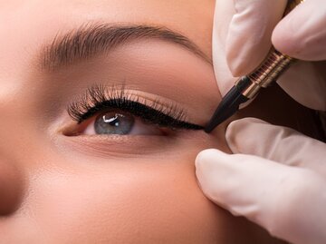 Frau wird schwarzer Eyeliner auf ihrem Lid aufgetragen | © Getty Images/Luda311