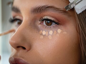 Nahaufnahme einer jungen Frau, auf deren Haut Concealer aufgetragen wurde | © Getty Images/FluxFactory