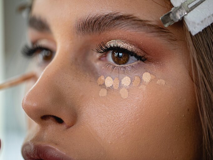 Nahaufnahme einer jungen Frau, auf deren Haut Concealer aufgetragen wurde | © Getty Images/FluxFactory