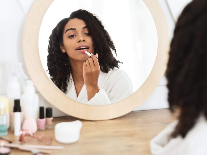 Frau trägt im Spiegel Lippenstift auf | © Getty Images/Prostock-Studio