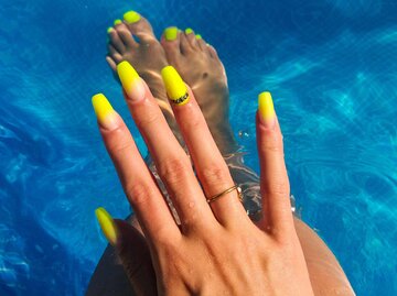 Frau mit neongelben Nägeln im Pool | © Getty Images/mikroman6