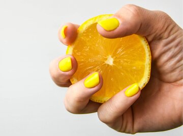 Hand mit gelben Fingernägeln und Zitrone | © Getty Images/Anastasiia Yanishevska