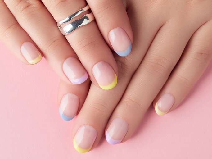 Hand mit bunt lackierten Nagelspitzen | © Getty Images/Dariia Chernenko