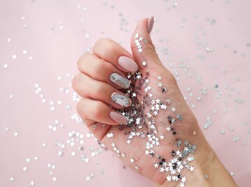 Hand mit lackierten Nägeln und Glitzersternen vor rosa Hintergrund | © AdobeStock/smile35