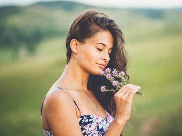 Frau riecht an Blumen | © Getty Images/Kajdi Szabolcs