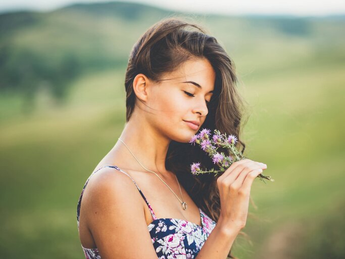 Frau riecht an Blumen | © Getty Images/Kajdi Szabolcs