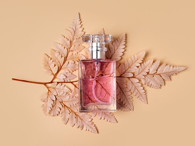 Parfüm Flasche mit Herbstblatt auf pastellfarbenem Hintergrund. | © shutterstock/Igisheva Maria